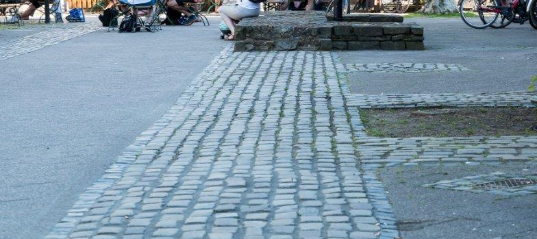 Kopfstein-Pflasterung und eine kleine Aufmauerung vor dem Alten Rathaus im Herzen der Dormagener Innenstadt. Die Steine liegen im Verlauf der römischen Lagermauer.