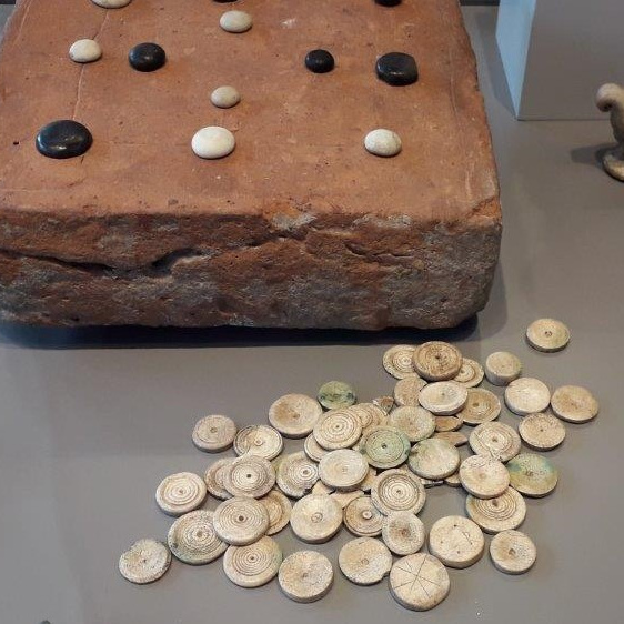 verschiedene römische Spielsteine liegen in einer Vitrine im Römisch-Germanischen Museum Köln