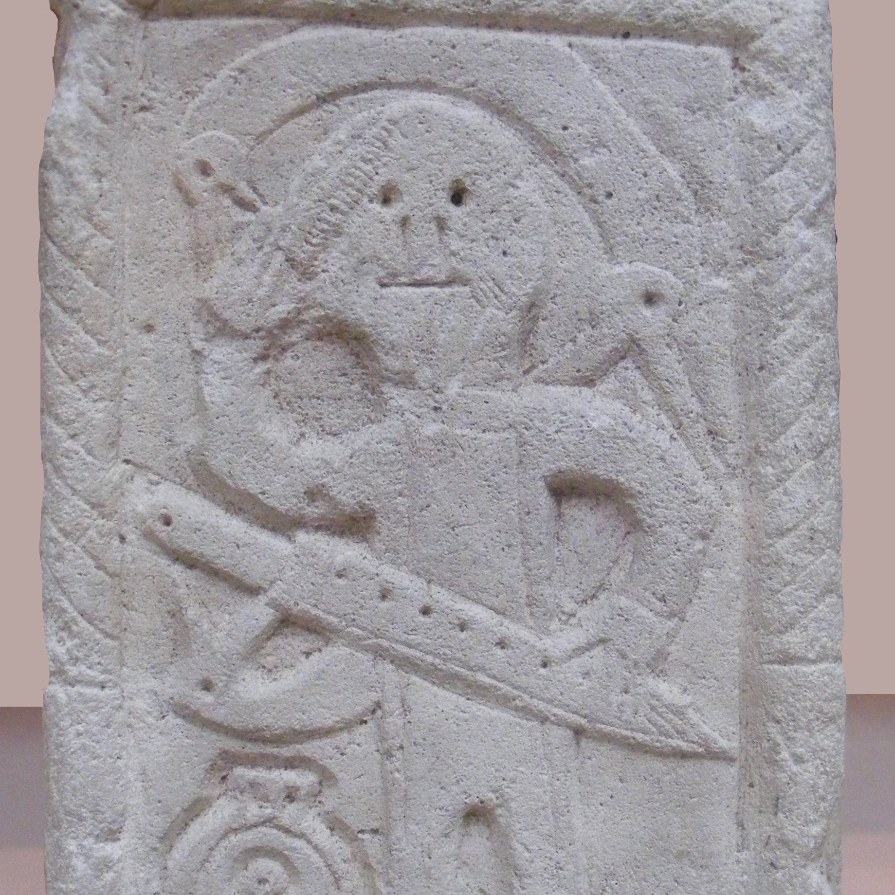 Foto des Grabsteins mit Flachrelief eines fränkischen Kriegers aus Niederdollendorf. Der Verstorbene hält einen Kamm in der Hand. erhobenen rechten Hand. LVR-LandesMuseum Bonn.