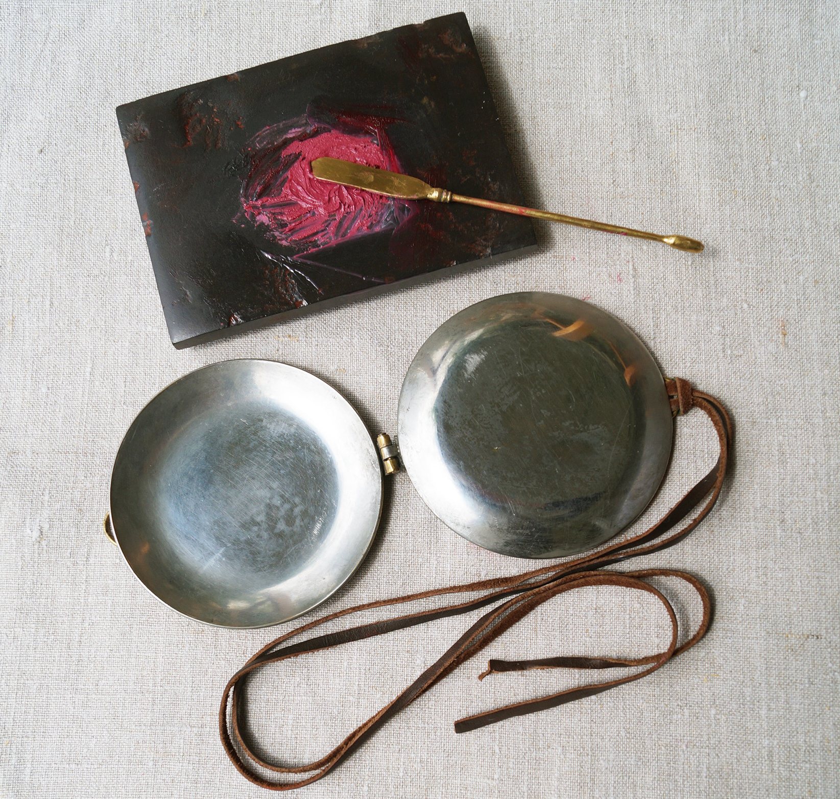 Rekonstruktion eines Klappspiegels nach einem Grabfund aus Wederath-Belginum, 1. Jh. n. Chr., Bronze mit verzinnten Innenseiten. Rekonstruktion: Aurificina Treverica. Dahinter Salbenstein mit frisch angeriebenem Rouge aus Krapplack.