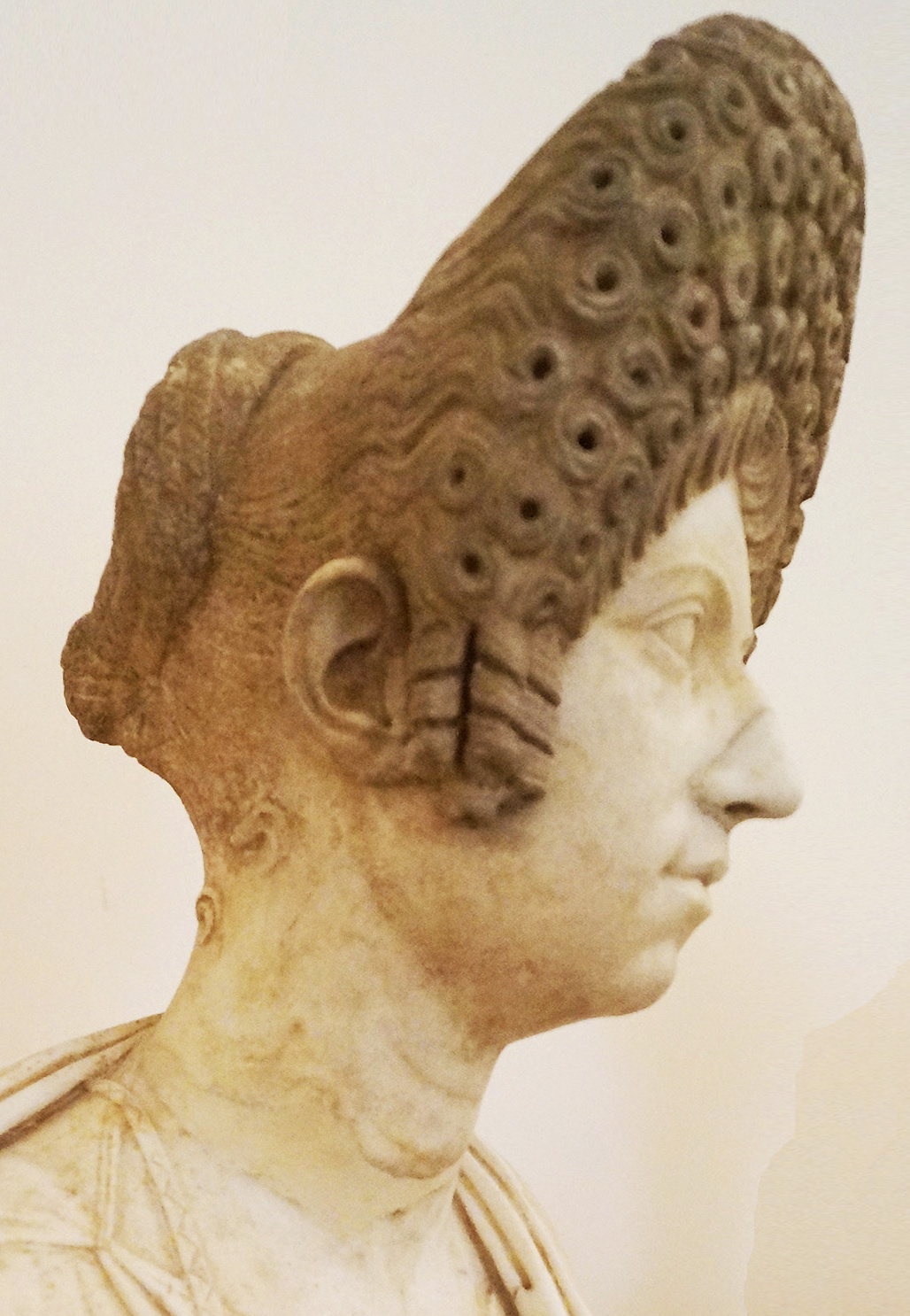 Foto der Büste einer römischen Matrone mit sog. flavischem Löckchentoupet; am Haar ist die ursprüngliche mittelbraune Bemalung noch gut erhalten. Museo Archeologico Nazionale Neapel.